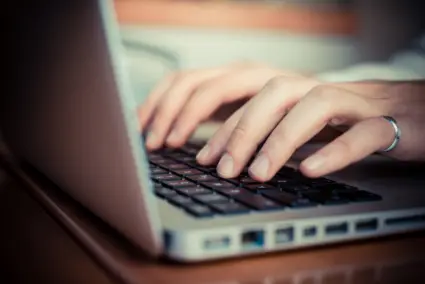 händer som skriver på en laptop