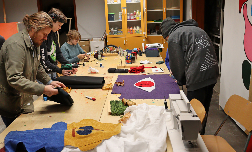 Eleverna sitter och står kring bord och jobbar med textil.