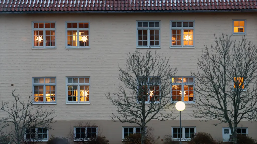 Fasad till kommunhuset med lysande julstjärnor i fönstren.