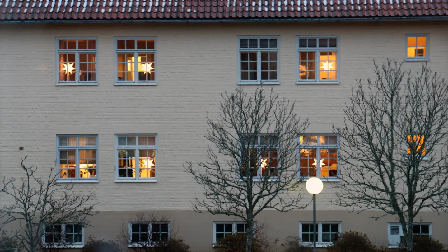 Fasad till kommunhuset med lysande julstjärnor i fönstren.