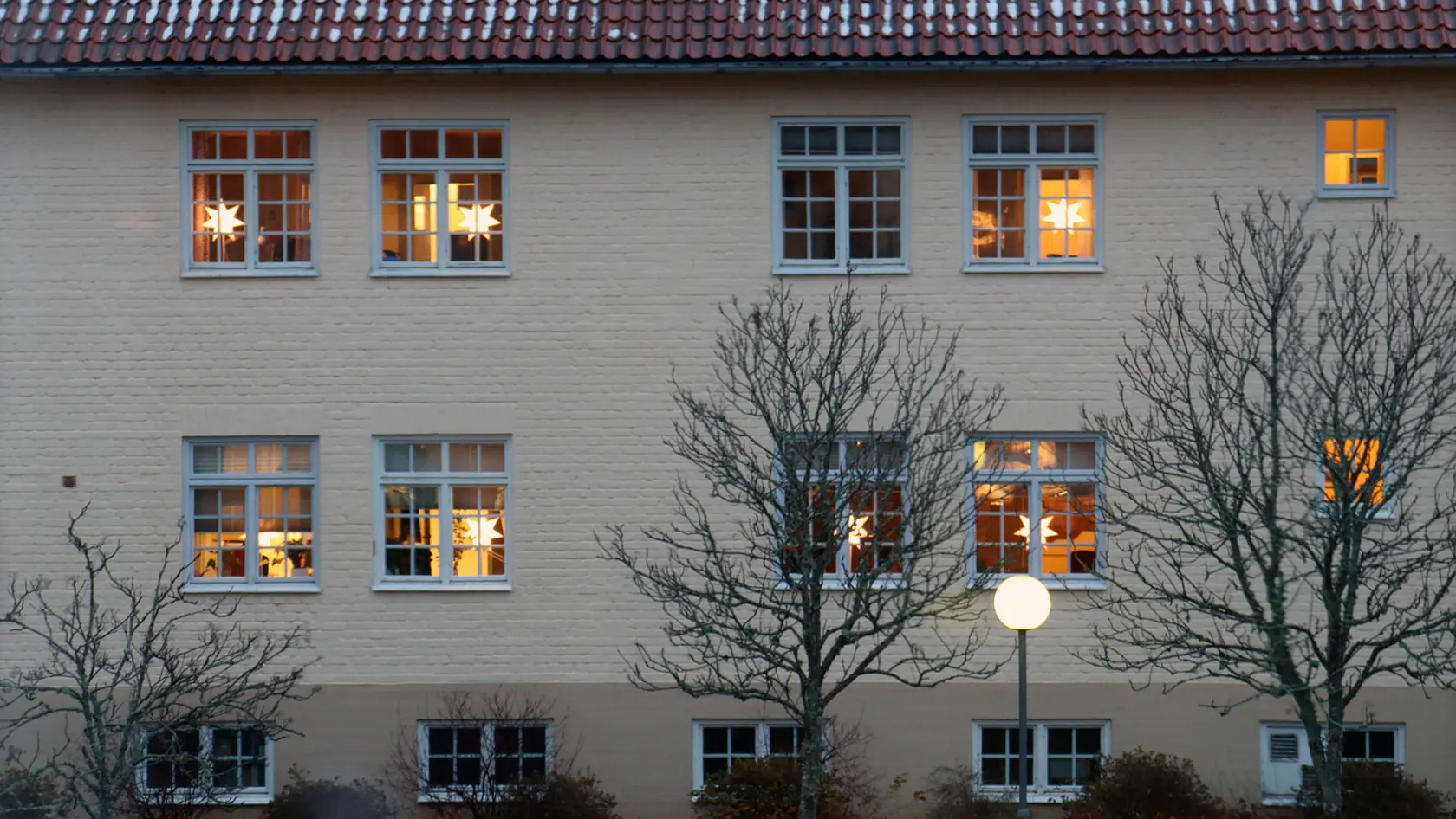 Fasad till kommunhuset med lysande julstjärnor i fönstren.