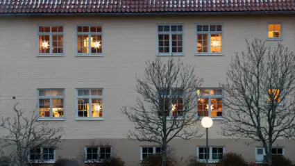 Fasad till kommunhuset med lysande julstjärnor i fönstren.