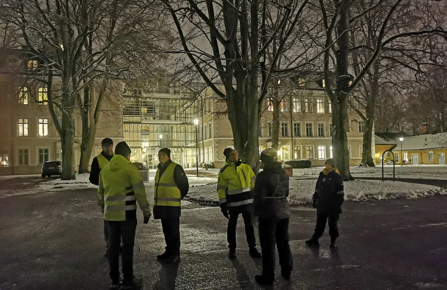 Grupp som står utanför biblioteket i kvällsmörker.