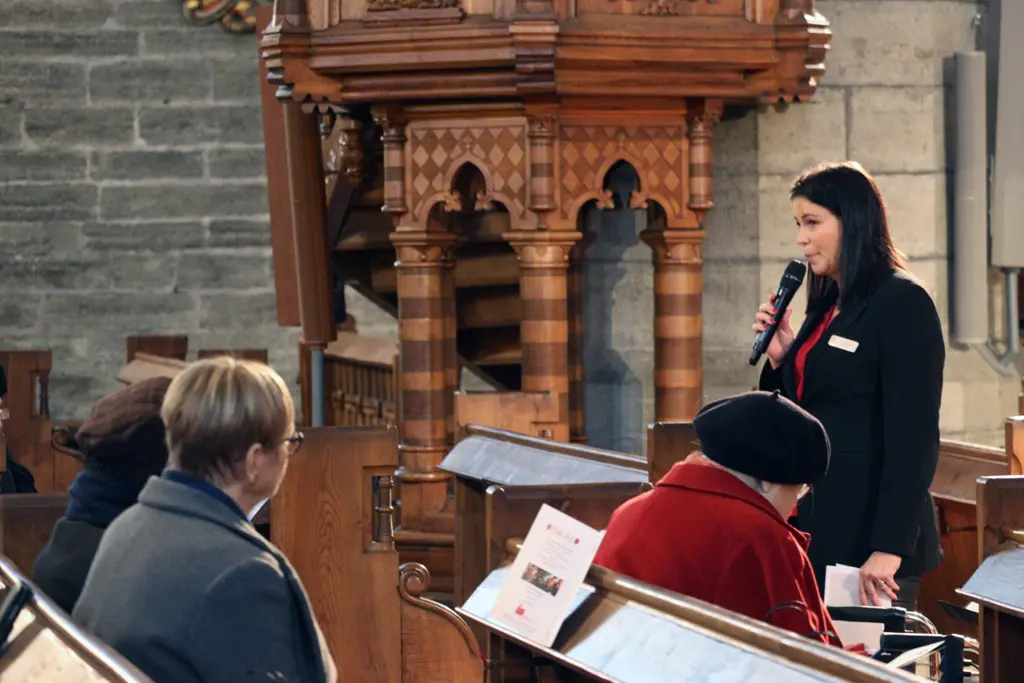 Socialchef Carolina strand med mikrofon i kyrkan.