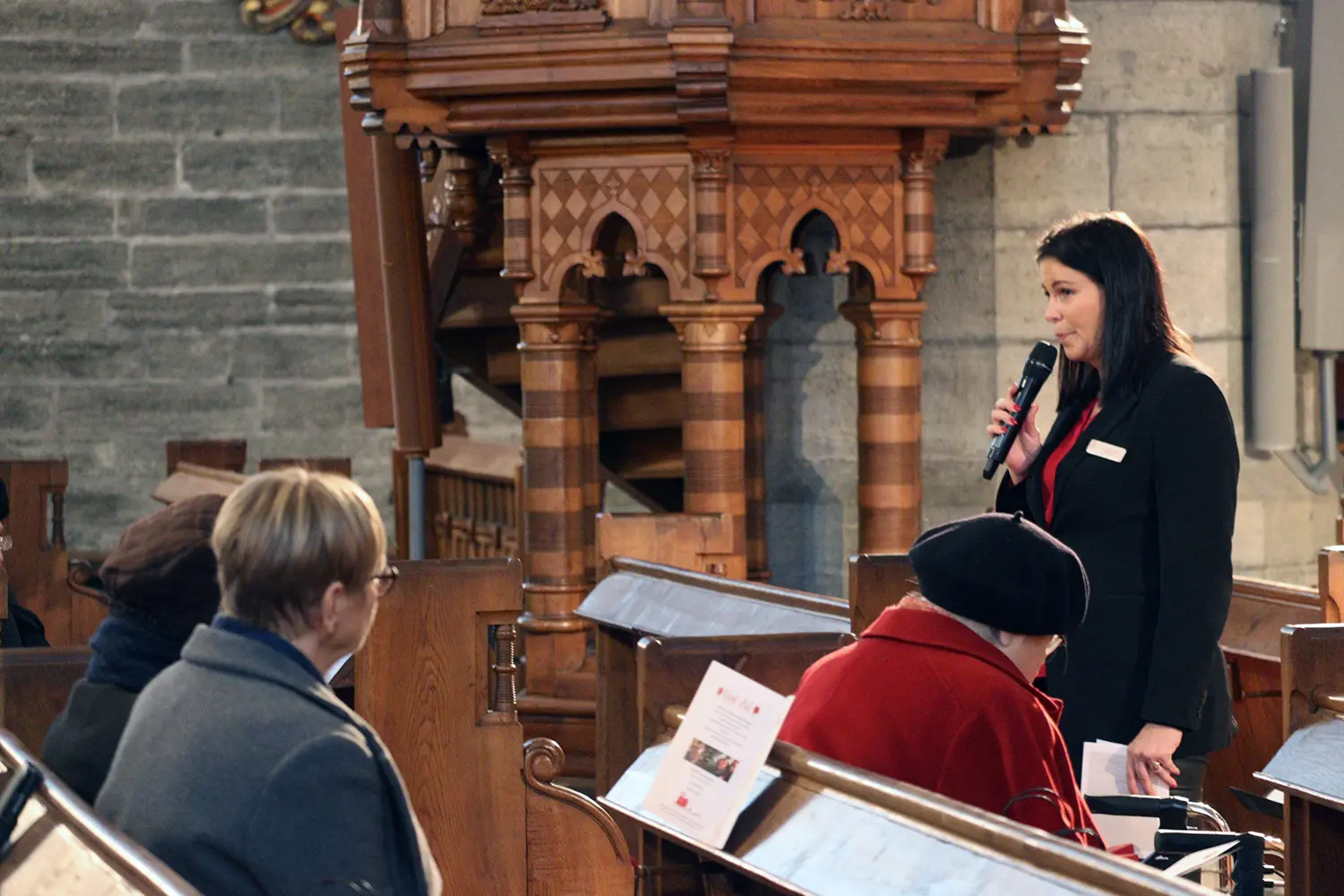 Socialchef Carolina strand med mikrofon i kyrkan.