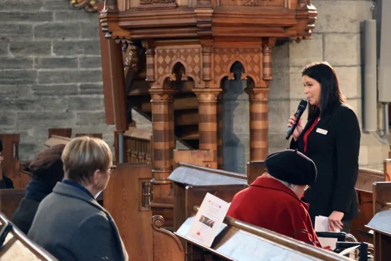 Socialchef Carolina strand med mikrofon i kyrkan.