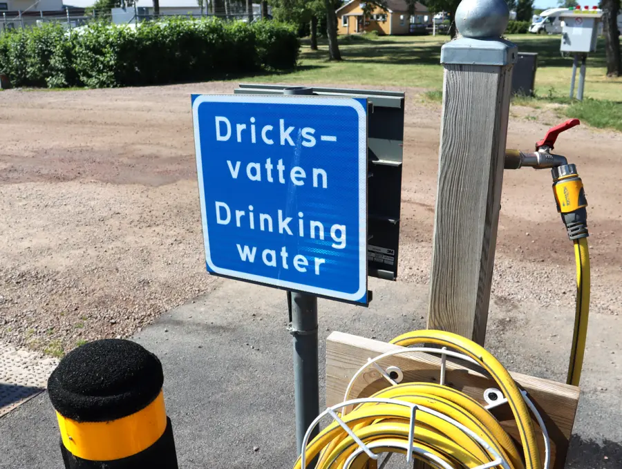 Slang och kran samt skylt med texten "dricksvatten"