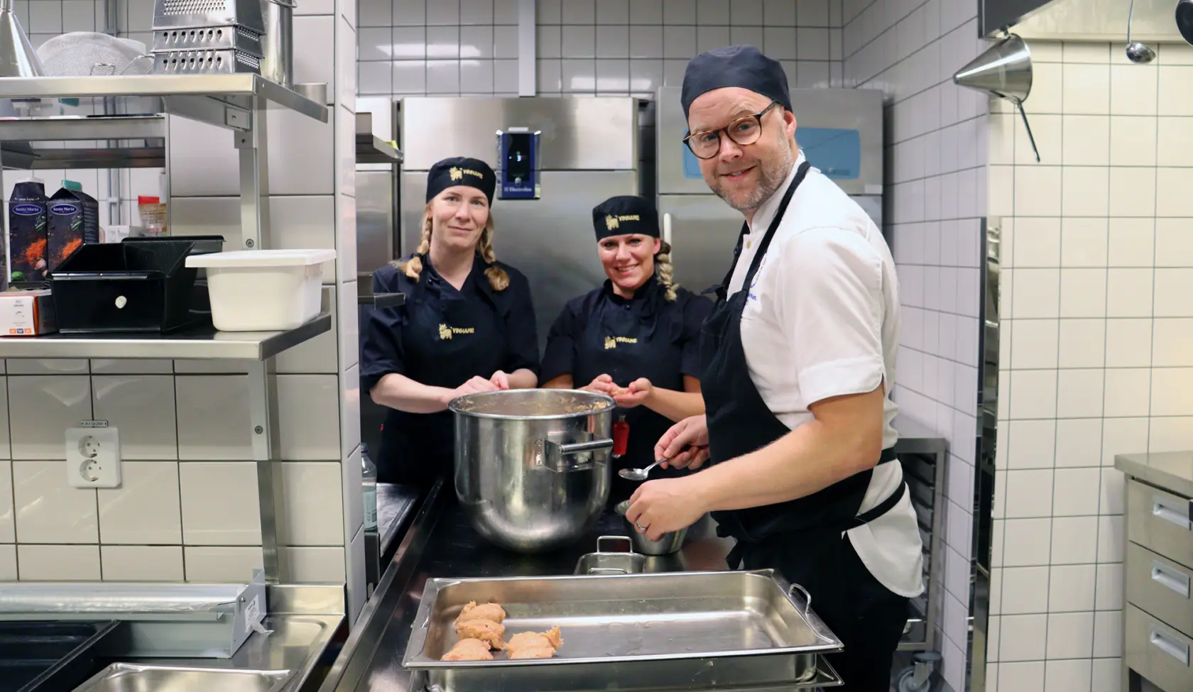Kockarna Matilda och Jenny står vid en bänk och jobbar tillsammans med Tomas Diederichsen