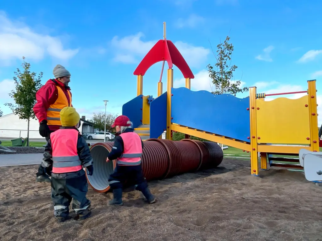 Förskolebarn på väg att krypa in i en tunnel bland lekredskapen.