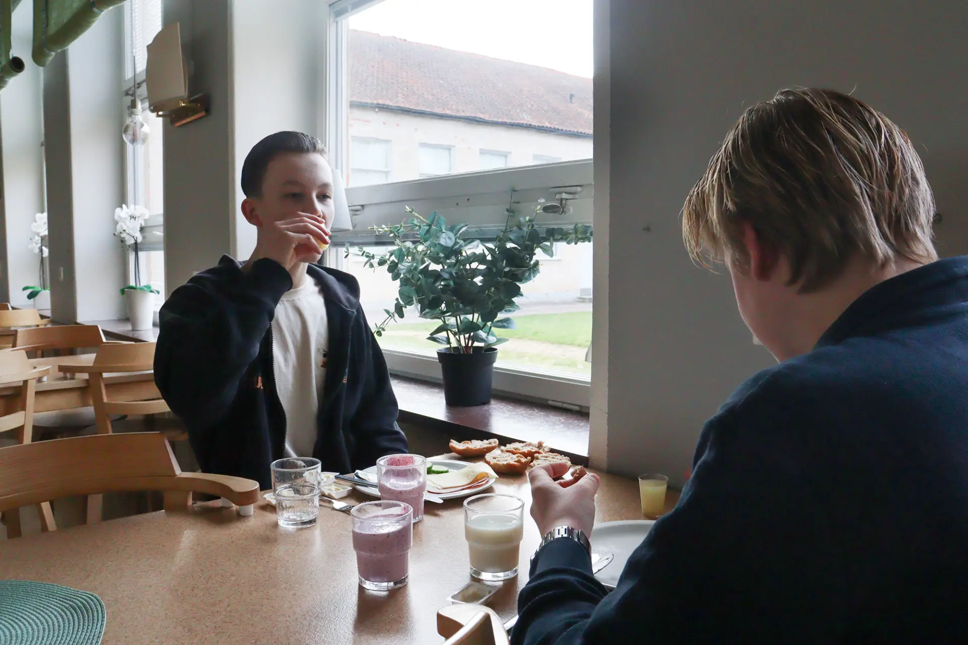 Två killar äter frukost i skolmatsal