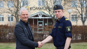 Peter Karlsson och Jens Öhmark tar i hand med kommunhuset i bakgrunden.