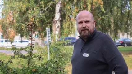 Johan framför grönskande träd och buskar.