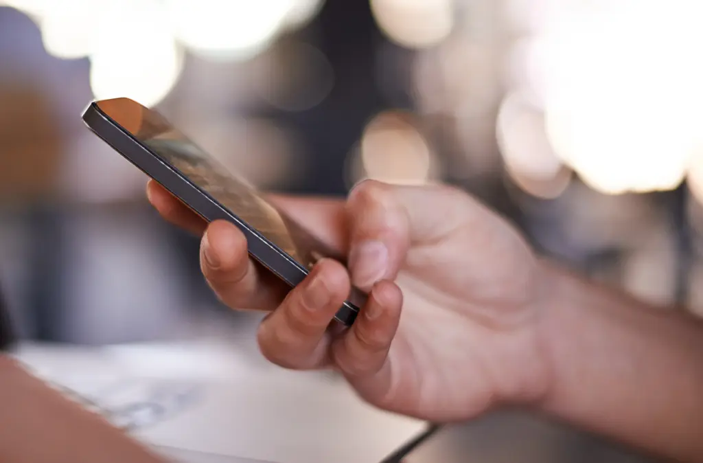Hand som håller i mobiltelefon.