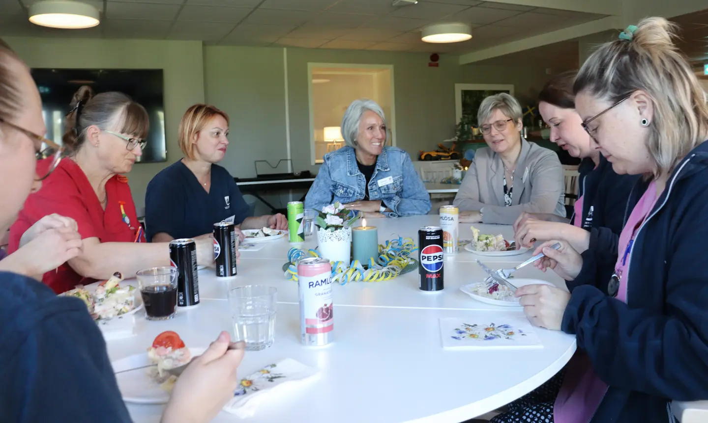 Grupp äter smörgåstårta kring bord