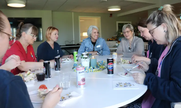 Grupp äter smörgåstårta kring bord