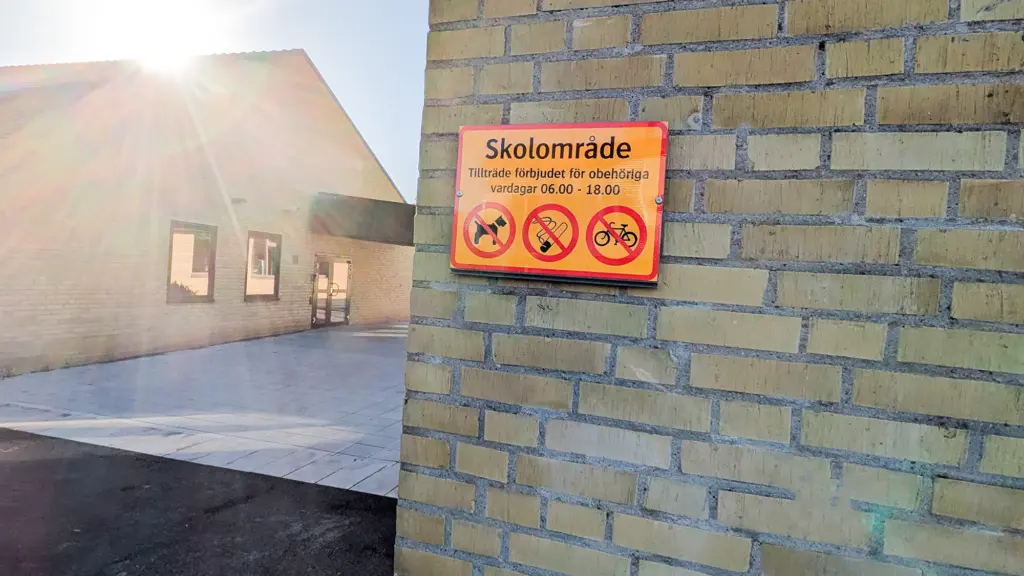 Skylt på husgavel som berättar att det är förbjudet att vistas på skolområdet under dagtid.