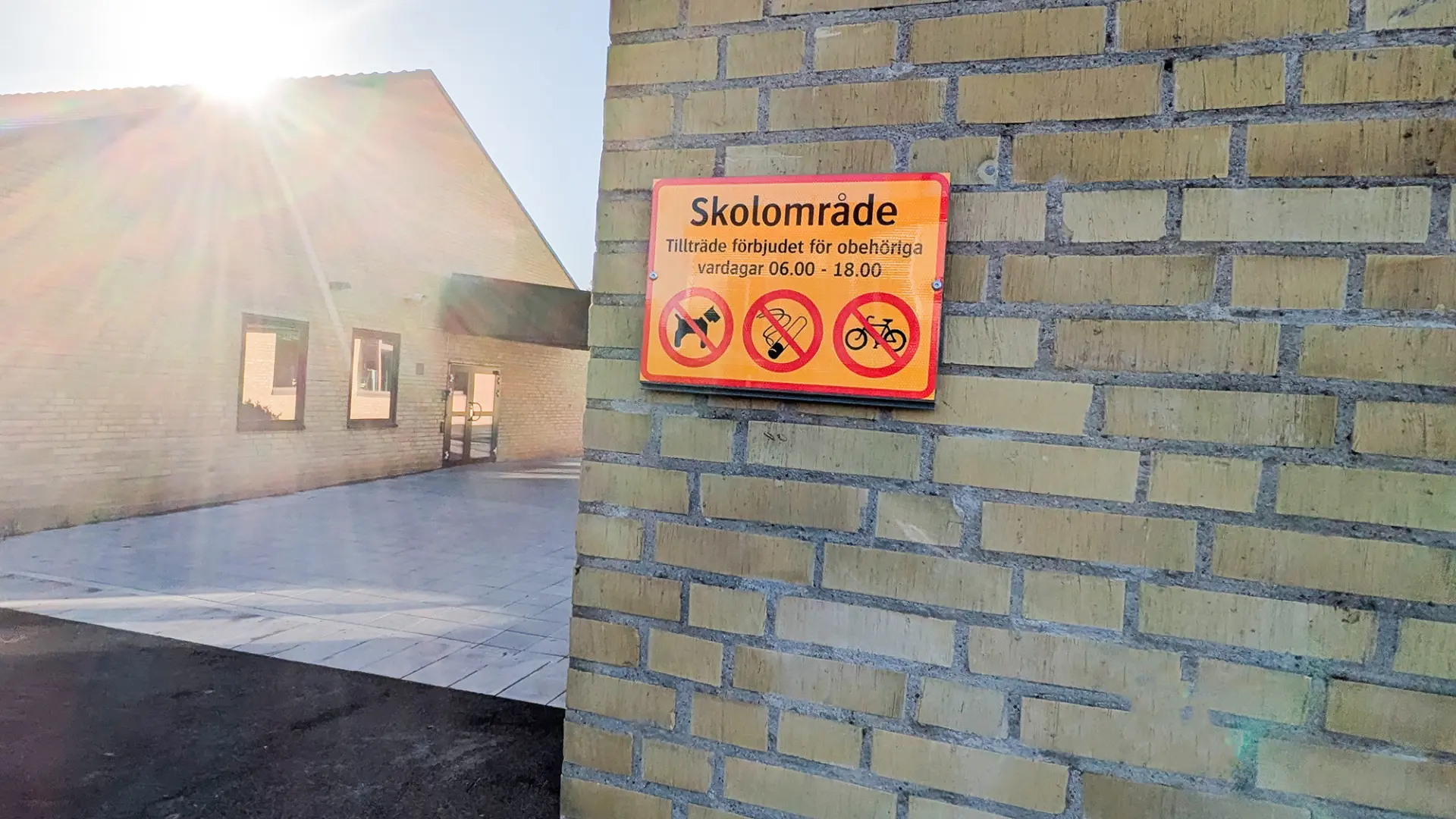 Skylt på husgavel som berättar att det är förbjudet att vistas på skolområdet under dagtid.