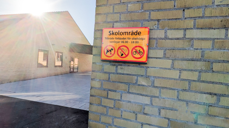 Skylt på husgavel som berättar att det är förbjudet att vistas på skolområdet under dagtid.