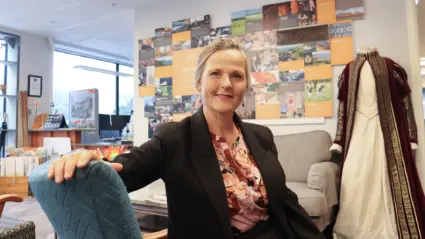 Stina sitter i en fåtölj med turistinformation på väggen bakom.
