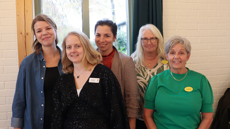 Fem kvinnor bakom bord.