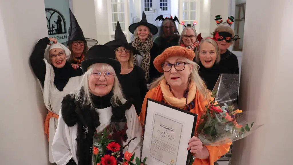 Ledare med diplom och blommor och bakom dem kvinnorna i gruppen.