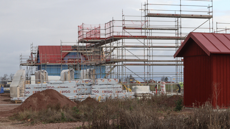 Byggarbetsplats med ställningar vid hus.