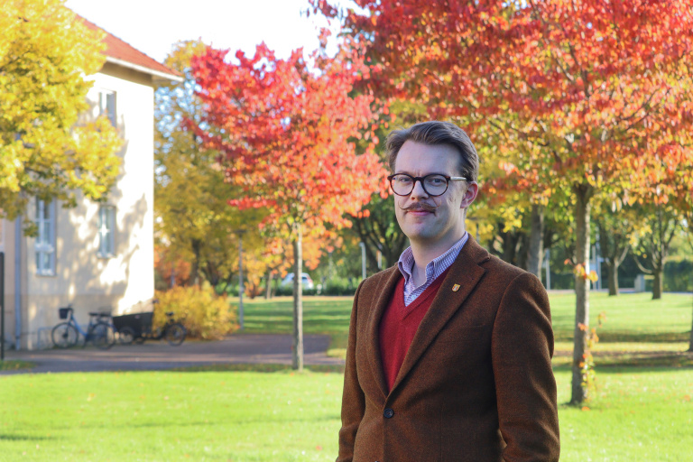 Richard framför kommunhuset i höstmiljö.