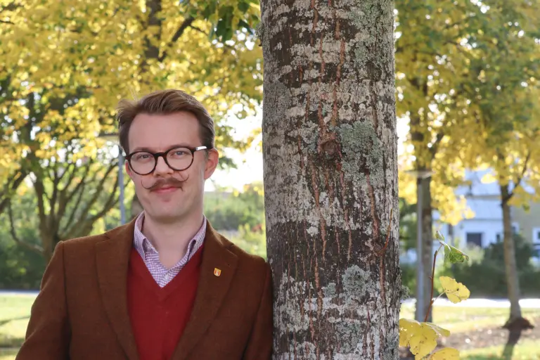 Richard lutar sig mot ett träd.