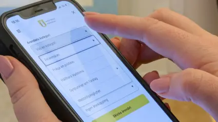 Händer håller mobiltelefon med app.