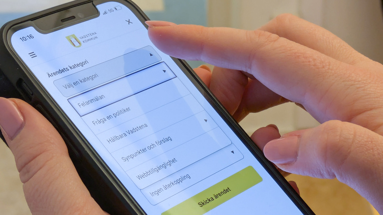 Händer håller mobiltelefon med app.
