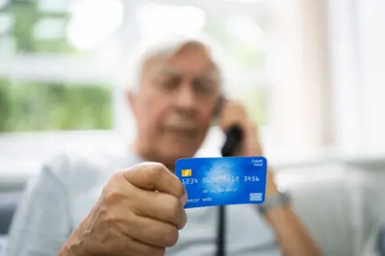 Äldre man i telefon och kreditkort.