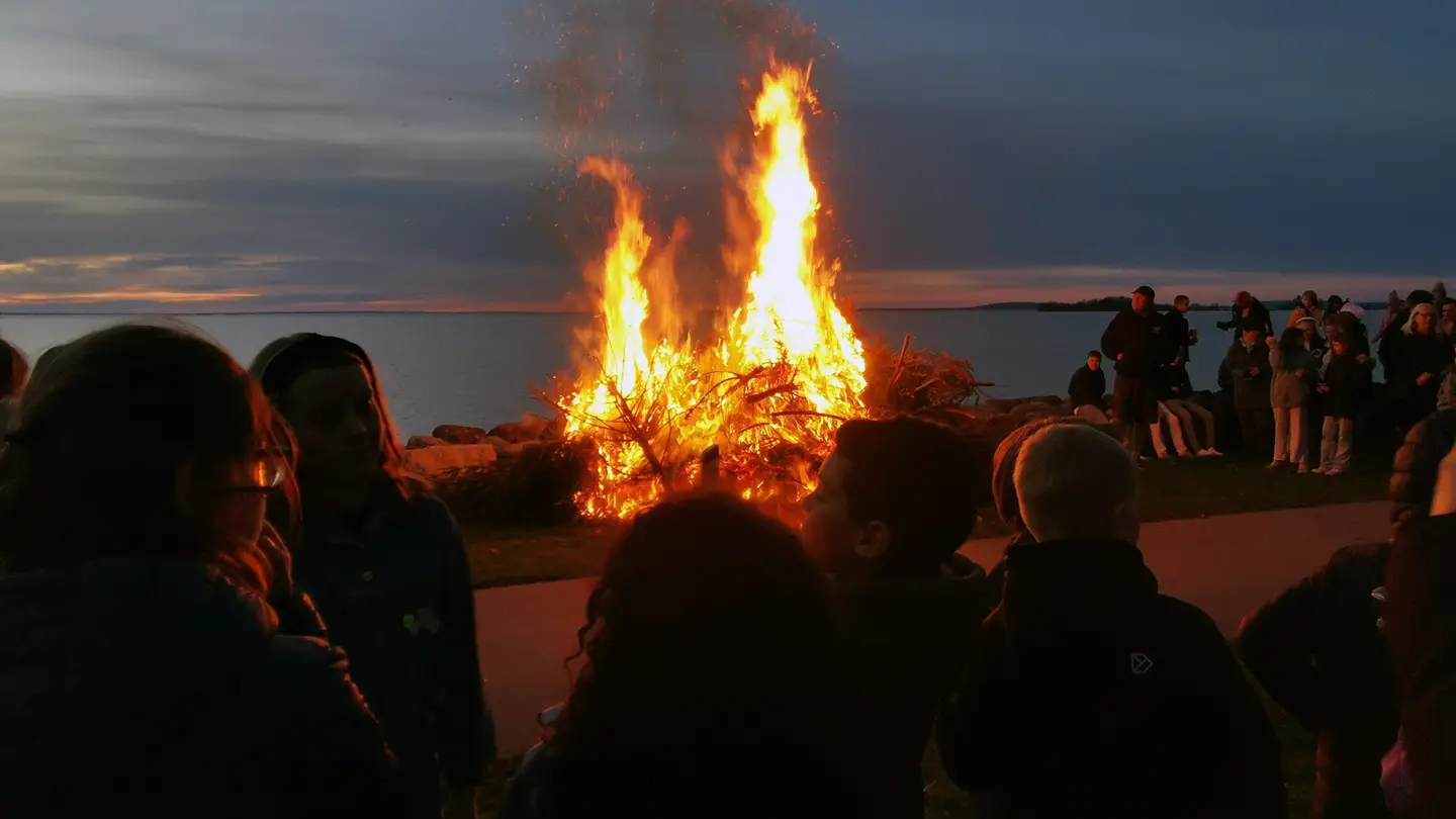 Människor kring majbål framför Vättern.