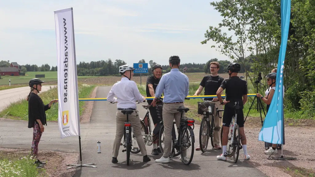 Cyklister samtalar från varsin sida av det band som ska ska klippas.