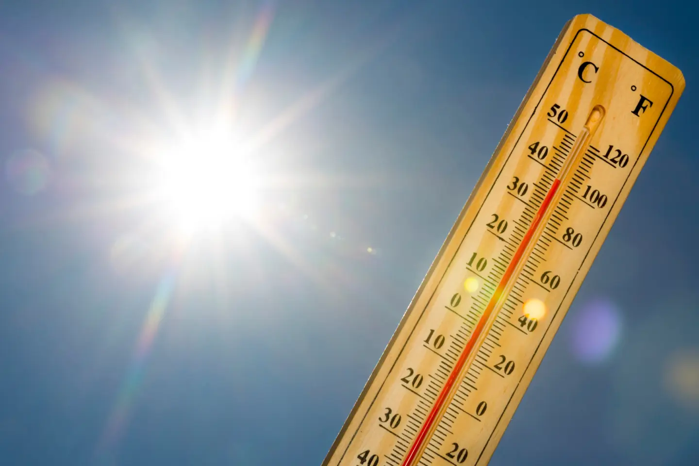 Termometer hålls upp mot gassande sol.