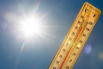 Termometer hålls upp mot gassande sol.